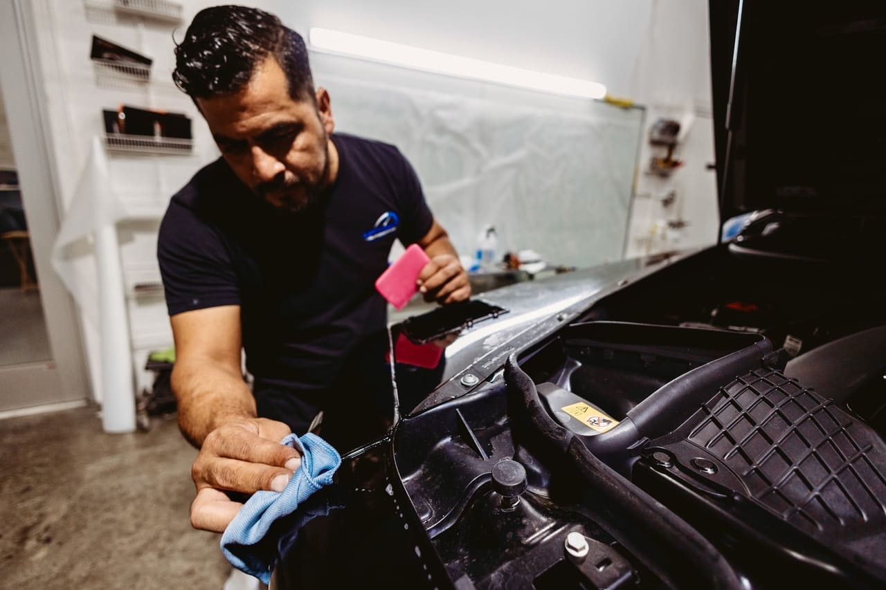 polishing paint on a black vehicle at a the best auto body shop in Houston, TX.